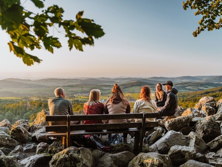 eine junge Freundesgruppe sitzt am Gipfel des Schafsteins und genießt die Abendsonne auf einer Bank