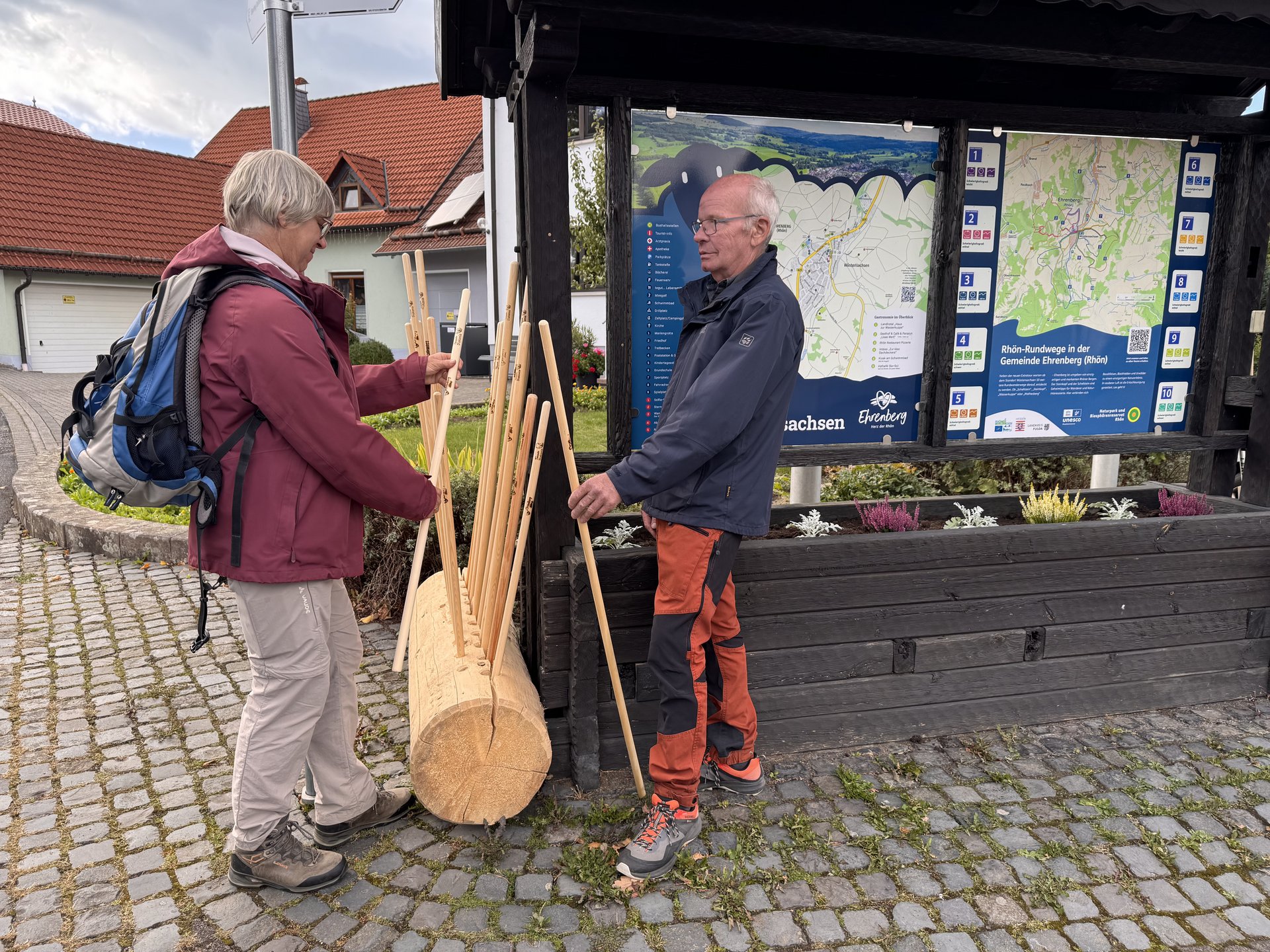 2 Wanderer schauen sich die Wanderstöcke an.