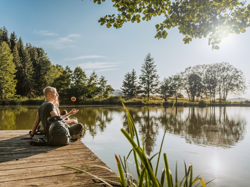 ein junges Pärchen sitzt auf der Bank am Reulbacher Weiher