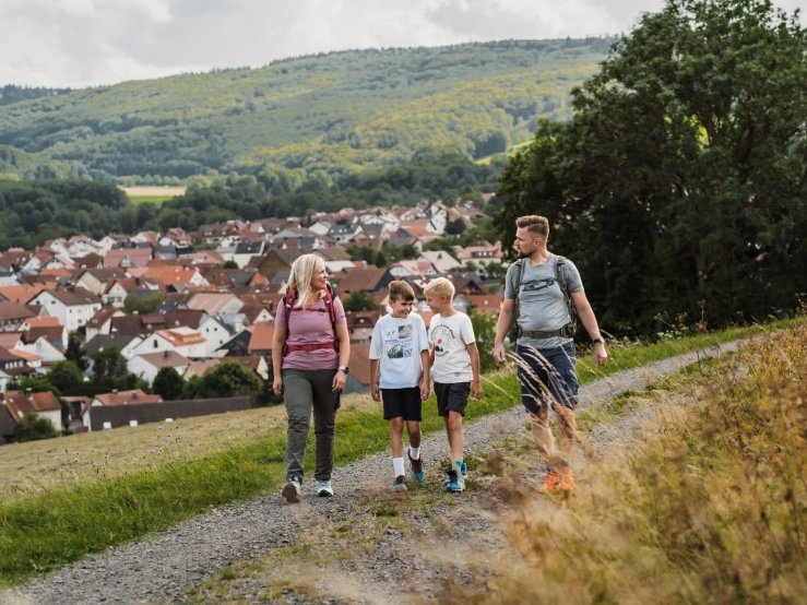 eine junge Familie wandert auf einem Schotterweg mit Blick auf Wüstensachsen