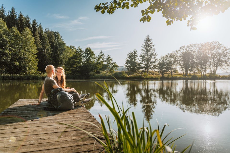 ein junges Pärchen sitzt auf dem Steg des Naturweiher Reulbachs
