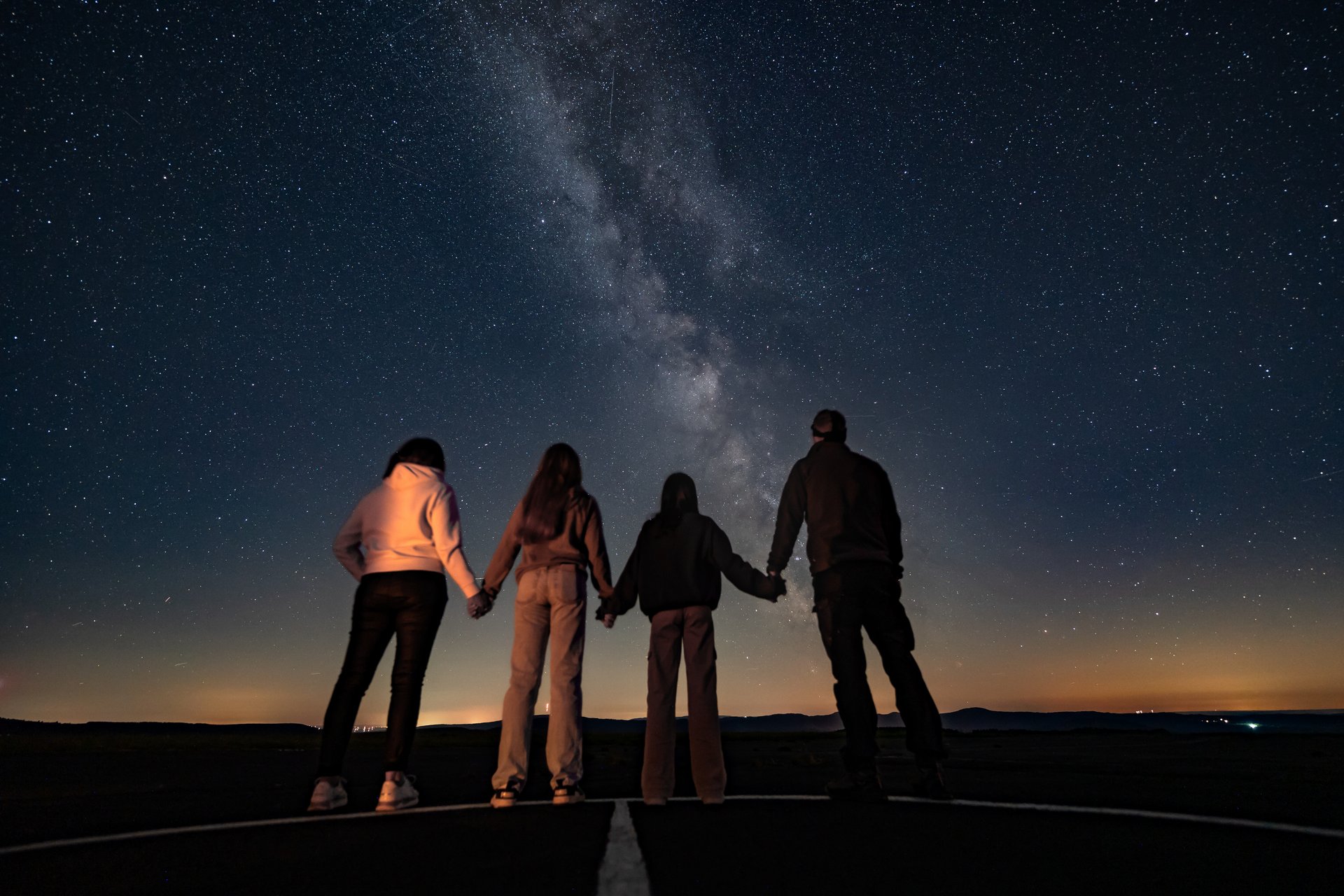 Eine Familie steht unter dem Sternenhimmel und schaut nach oben.