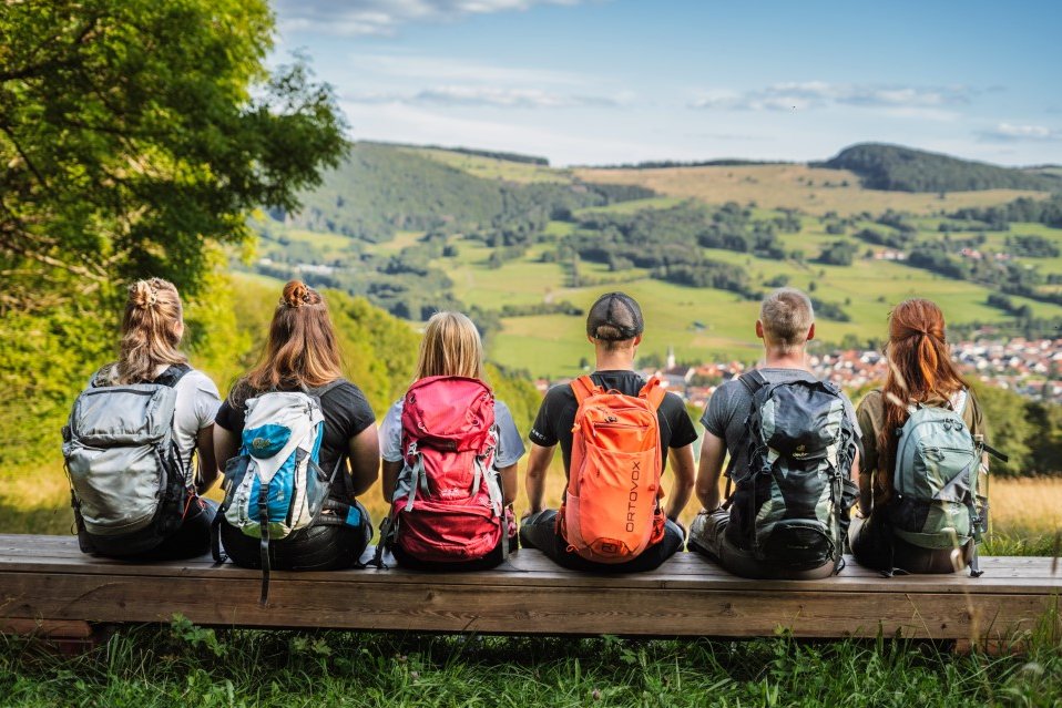 eine Gruppe von jungen Leuten sitzt gemeinsam auf der XXL-Bank Hutebuche