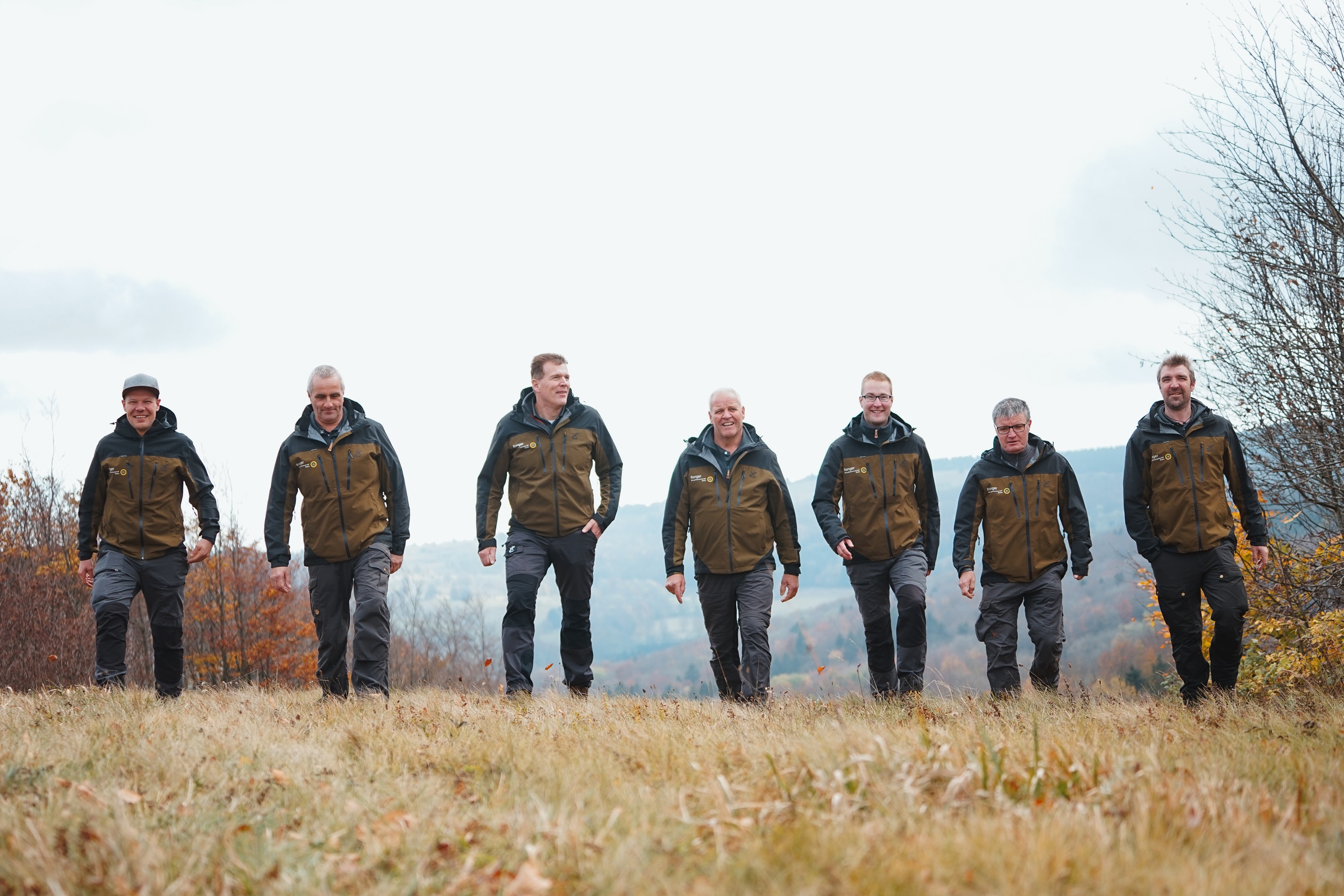 Eine Gruppe von Rangern läuft eine Wiese hoch