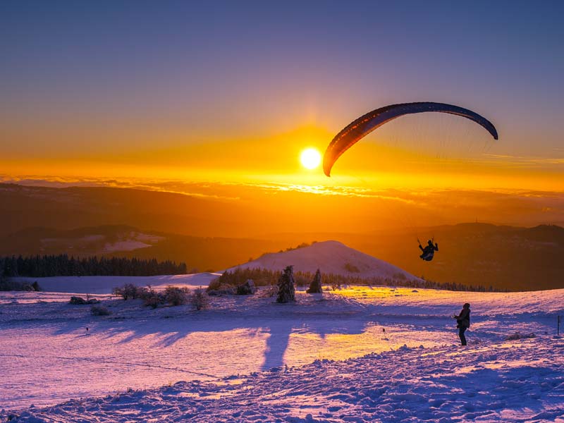 Paraglider im Winter bei Sonnenuntergang