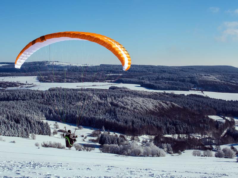 Paraglider fliegt im Winter von der Wasserkuppe aus