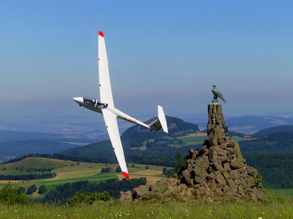Segelflieger fliegt am Fliegerdenkmal vorbei