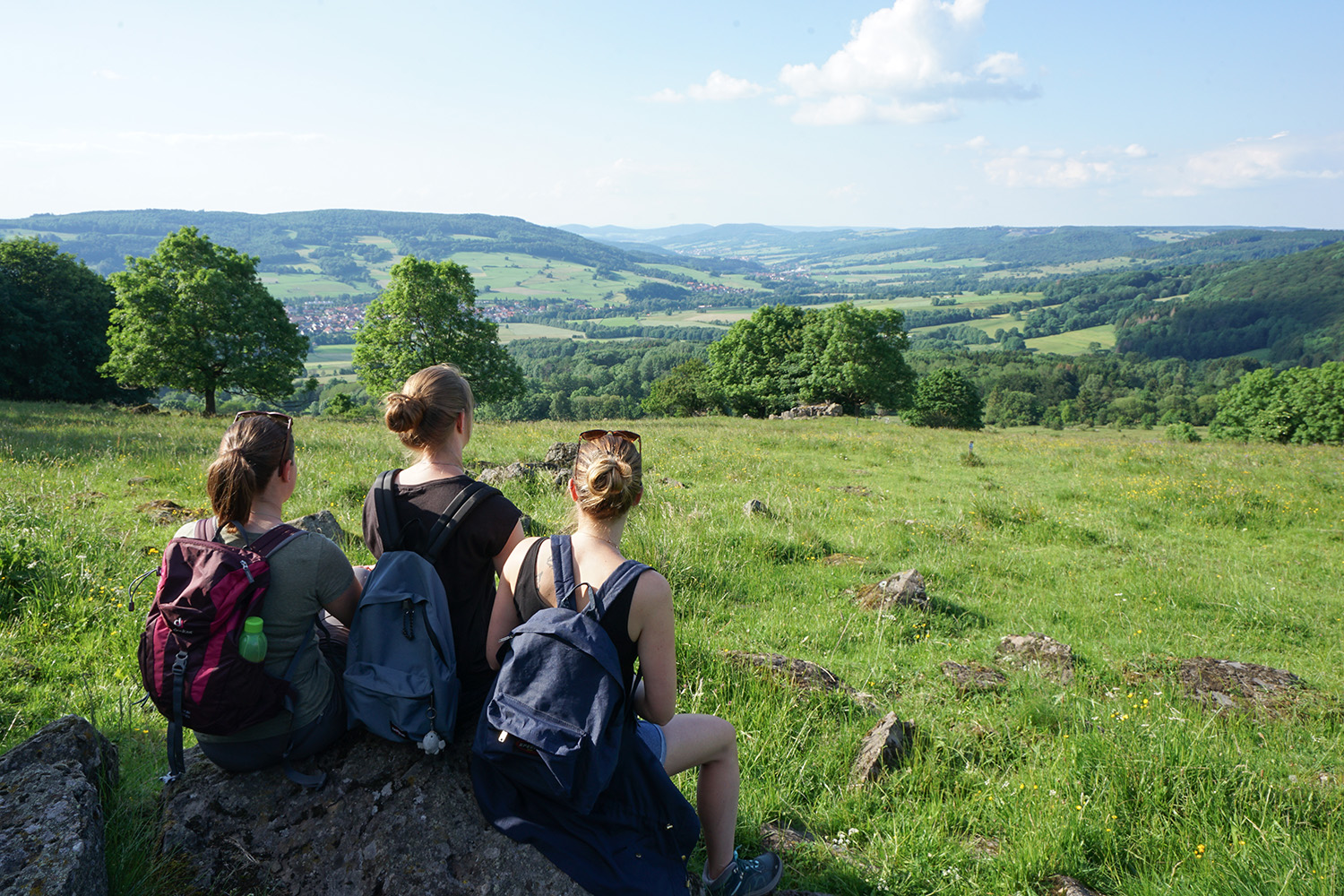 Blick ins herrliche Ulstertal, 3 Wanderinnen sitzen auf einem große Stein und genießen den Ausblick
